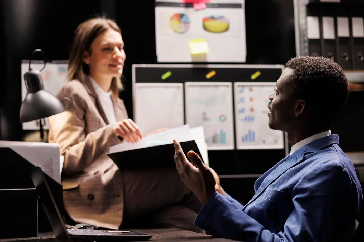 Diversos trabajadores del depósito analizan un registro burocrático y trabajan horas extra en un informe contable en la sala de archivo. Profesionales de negocios revisan documentos administrativos en el repositorio corporativo.