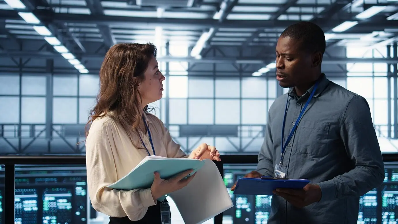 Administradores alegres se reúnen en un centro de datos para revisar informes mientras se dan la mano.