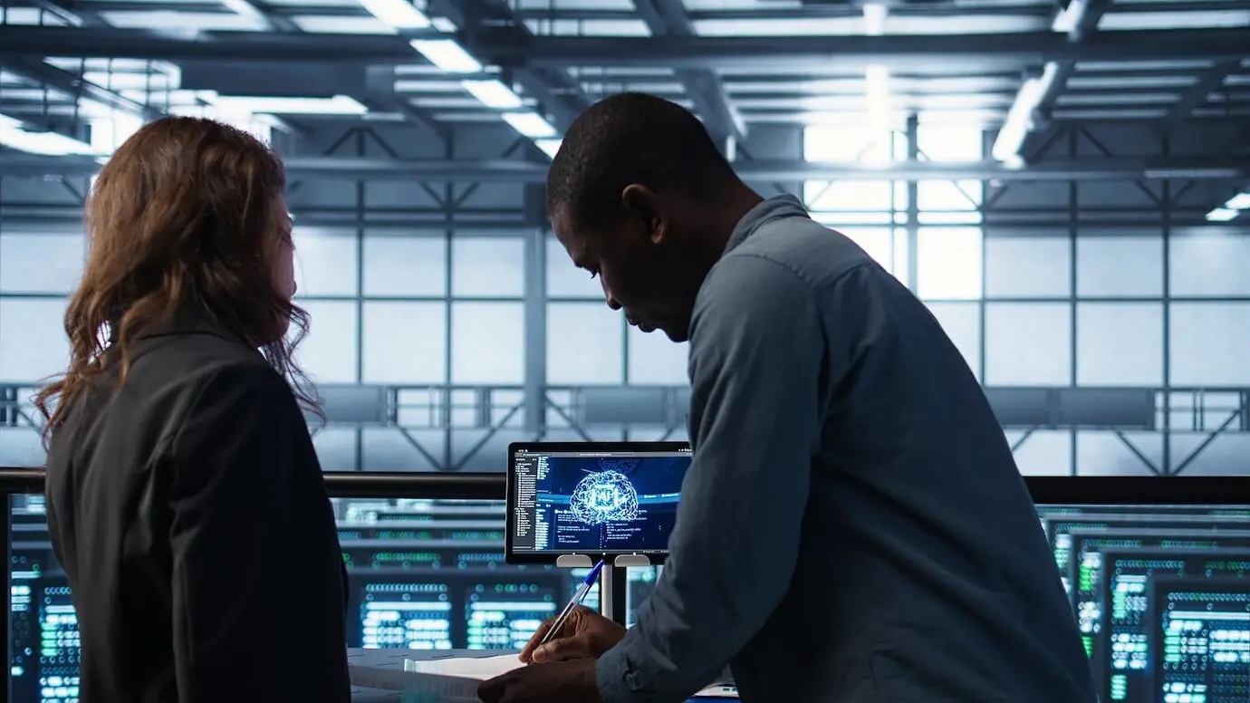 Un gerente se reúne con un cliente en un centro de datos para revisar archivos, dándose la mano.